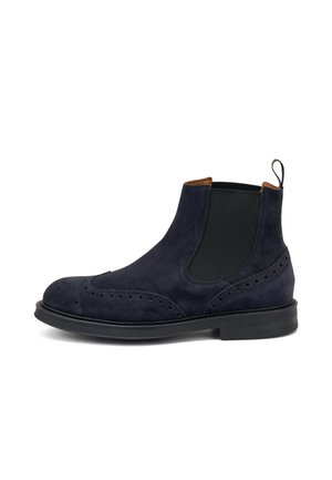 Botas Chelsea de ante azul marino con paneles laterales elásticos, detalle de brogue, puntera redonda y suela de goma negra; lengüeta en la parte trasera para facilitar su uso.
