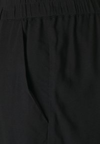 Svarta tygbyxor med elastisk midja och sidofickor, med en mjuk textur och avslappnad passform.