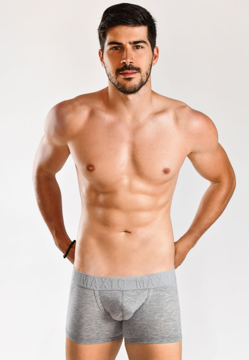 Boxer aderente in cotone grigio con una cinturalogata, caratterizzato da un design aderente e una texture liscia, esposto su un modello maschile senza maglietta.