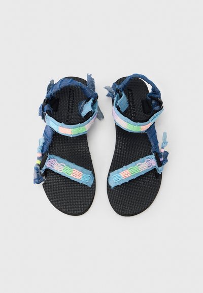 Niebieskie dżinsowe sandały z fakturowanymi czarnymi podeszwami, z kolorowymi, tkanymi paskami w pastelowych odcieniach i postrzępionymi krawędziami dla swobodnego wyglądu.