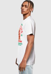 T-shirt in cotone bianco con una stampa grafica colorata di pizza, testo in rosso e verde, e una vestibilità comoda con maniche corte.
