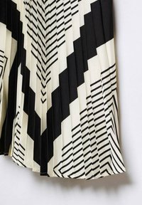 Gonna plissettata con un motivo geometrico in bianco e nero caratterizzato da zigzag e righe. Realizzata in tessuto leggero, con una texture liscia.
