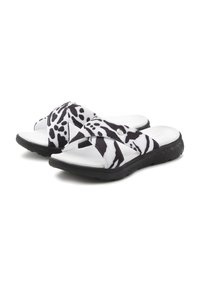 Black and white slide sandals featuring a cross strap design, textured rubber sole, and a cow print pattern on synthetic material.