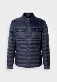 Temno modra napihnjena jakna z gumbi na sprednji strani, dvema prsnikoma in ovratnikom. Narejena iz lahkotnega, sijočega materiala s prešito teksturo.