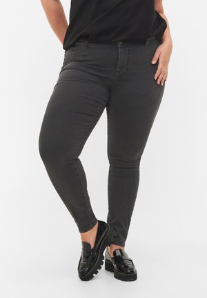 Jean skinny gris en denim, avec un design classique à cinq poches et une finition légèrement délavée. Associés à des mocassins noirs brillants.