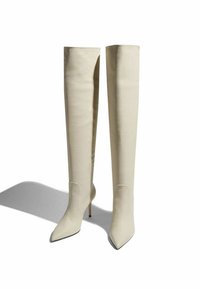 Botas de tacón alto de color crema hasta la rodilla con punta afilada. Material suave y estructurado con un diseño elegante y detalles de costura sutiles.