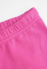 Różowa bawełniana tkanina z marszczonym elastycznym paskiem w talii, ukazująca gładką fakturę i równe szwy. Zbliżenie podkreślające kolor i materiał.