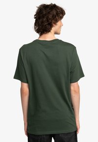 Grøn bomulds t-shirt med rund hals og korte ærmer, præsenteret fra ryggen, med et ensfarvet design og en afslappet pasform.