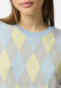 Suéter ligero con un patrón de rombos en tonos pastel de amarillo, azul y gris, con un cuello acanalado y una textura de tela especial.