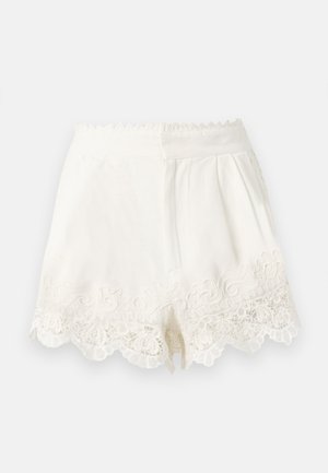 Hvide højtaljede shorts med bølgede kanter og detaljeret blondebroderi langs kanten, med en skjult lynlås fortil.