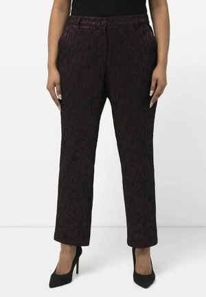 Pantalons violets imprimés avec un motif floral texturé, dotés d'une fermeture à boutons, de passants de ceinture et de poches, associés à des escarpins noirs.