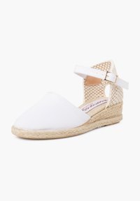 Espadrille en toile blanche avec un bout pointu, un talon compensé en jute et une bride de cheville réglable avec un design tissé à l'arrière.