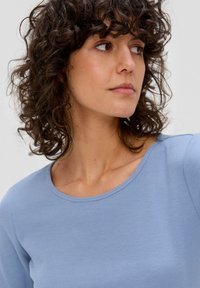 Lichtblauwe ribgebreide longsleeve top met een ronde halslijn en een getailleerd ontwerp. De stof heeft een zachte textuur en een subtiele rek.