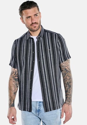 Short-sleeve button-up shirt in black and white vertical stripes, featuring a relaxed fit, soft fabric, and a small logo patch on the chest.