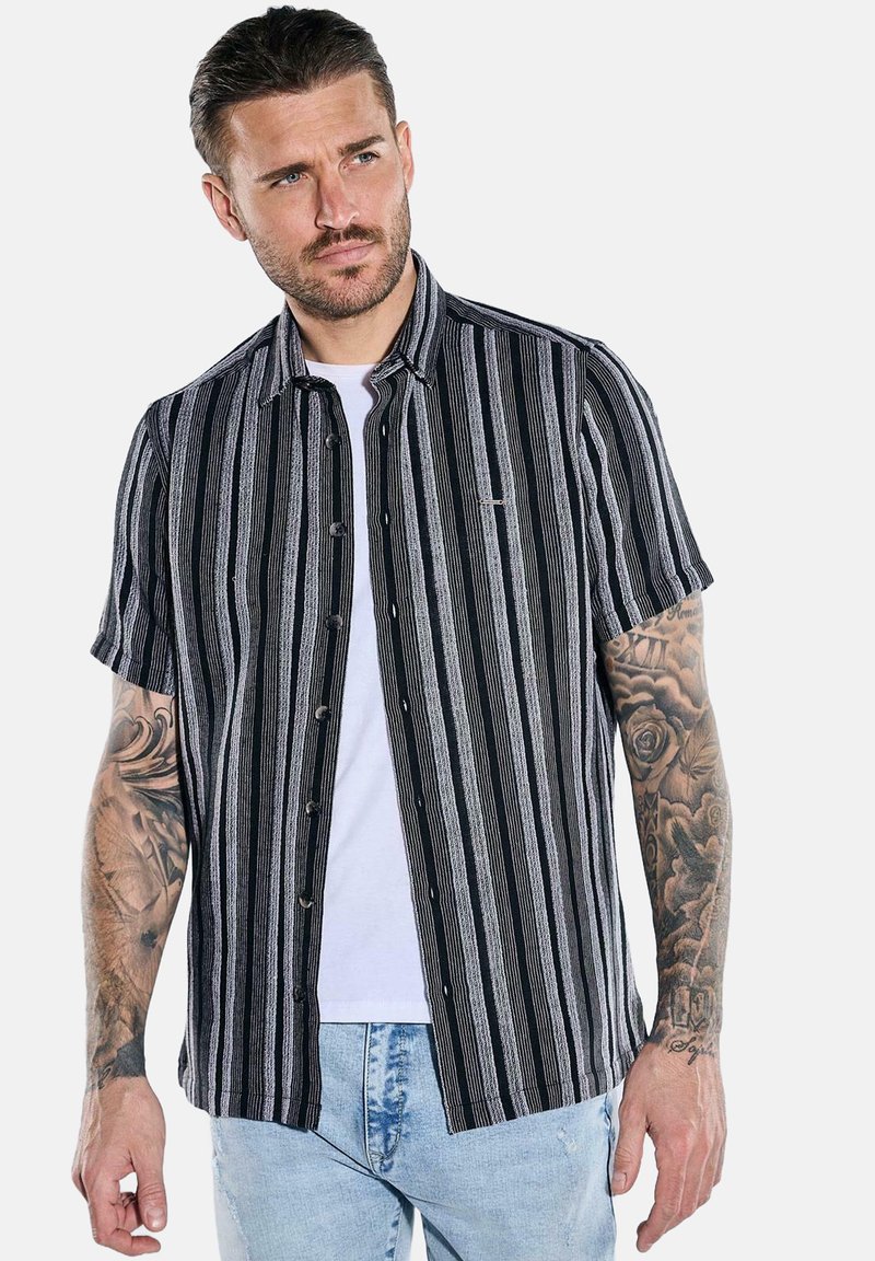 Kurzarm-Hemd mit Knopfleiste in schwarz-weißen vertikalen Streifen, mit lockerer Passform, weichem Stoff und einem kleinen Logo-Patch auf der Brust.