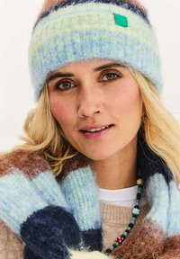 Dzianinowa czapka z wełny w pastelowe niebieskie i zielone paski z akcentem w kolorze morskim. W zestawie z wielokolorowym szalikiem z poziomymi paskami.