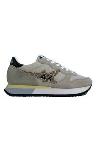 Scarpa sportiva beige realizzata in suede e rete, con un logo dorato glitterato, lacci bianchi e un tallone nero su una suola a contrasto.