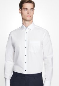 Witte lange mouwen overhemd met een klassieke kraag, voorzien van donkerblauwe knopen en een borstzak. Glad stof en slim fit.