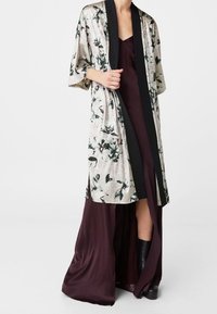 Długi, kwiatowy kimono z teksturowanej jasnoszarej tkaniny i czarnymi akcentami, w zestawieniu z głęboko burgundową satynową sukienką z rozcięciem do uda.