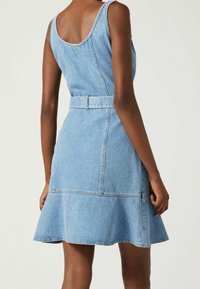 Farkkumekko, jossa istuva yläosa, leveät olkaimet ja levenevä helma. Vyötäröllä vyö, vaaleansininen väri ja ompelukoristelut.