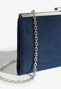 Námořnicky modré semišové psaníčko se stříbrným kovovým rámem a řetízkovým popruhem, s hladkou texturou a jednoduchým obdélníkovým designem.