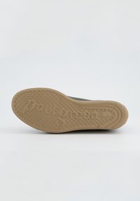 Semelle de chaussure en caoutchouc brun clair, motif texturé avec des grips circulaires, comporte un nom de marque gravé, forme courbée avec un léger talon.