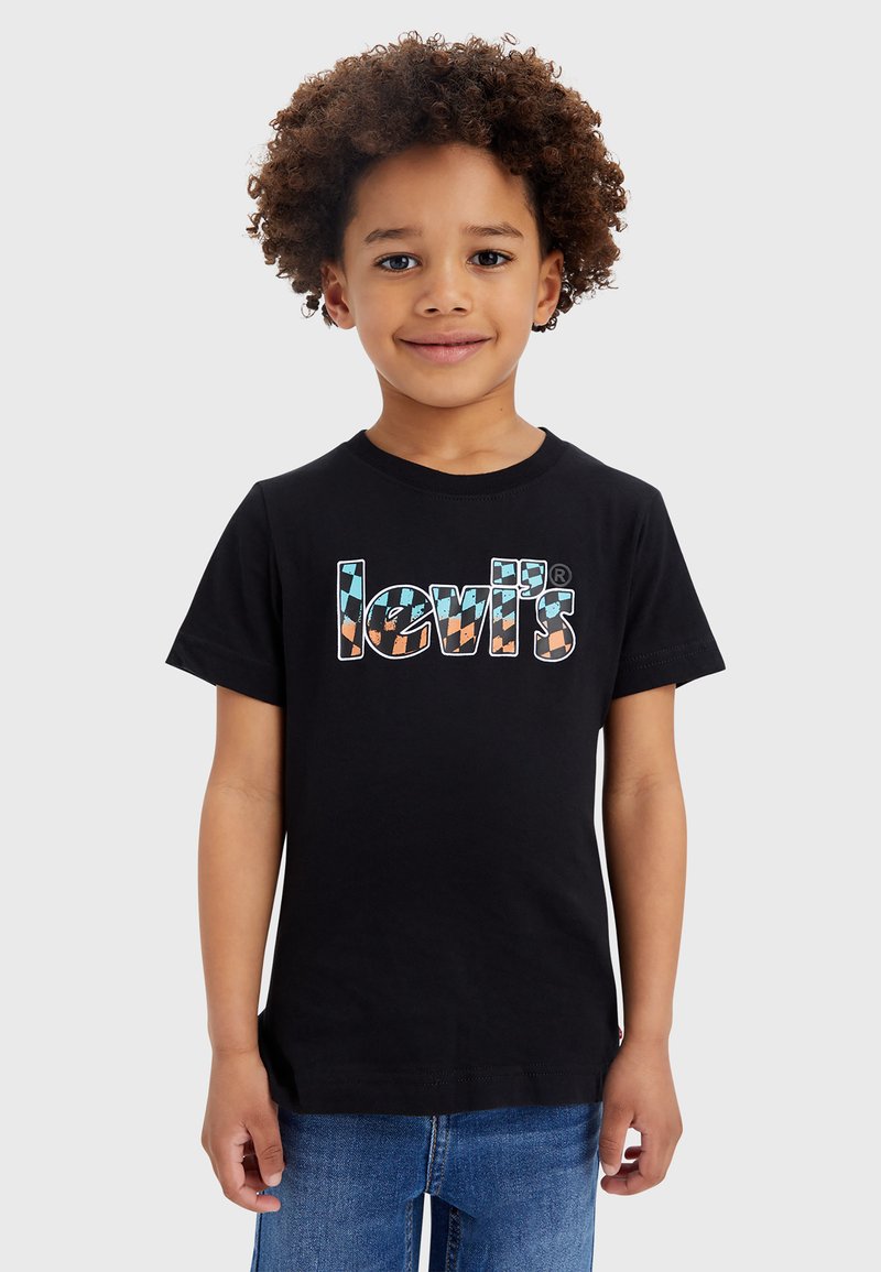 Zwarte katoenen t-shirt met een kleurrijk, patroon van het "Levi's" logo. Ronde halslijn, korte mouwen, op maat gemaakte pasvorm. Gecombineerd met een blauwe spijkerbroek.