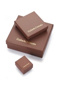 Hnedé darčekové krabice rôznych veľkostí s zlatým textom "Rafaela Donata" a hladkým, lesklým povrchom.