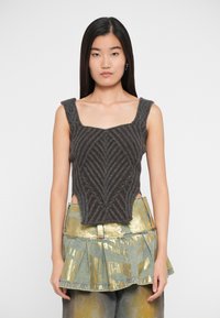 Sivi pleteni crop top s geometrijskim uzorkom, s kvadratnim izrezom i širokim trakama, u kombinaciji s metalik zlatnom plisiranom suknjom.