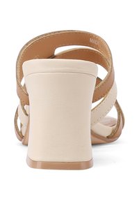 Sandali con tacco alto beige, con cinturini incrociati e una finitura liscia. Il tacco ha una texture opaca, che completa il design complessivo.