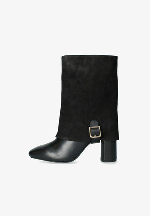 Botín negro hasta el tobillo con parte superior de ante, punta afilada, tacón grueso y una hebilla decorativa en el costado, con una puntera de cuero suave.