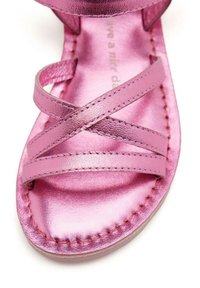 Sandal in metallo rosa con design a tracolla incrociata, suola piatta e dettagli cuciti. Texture liscia con una finitura lucida.