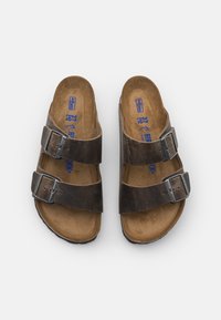 Braune Ledersandalen mit zwei verstellbaren Schnallen, Korkfußbett und Gummisohle. Auffällig durch ihr minimalistisches Design und Erdtöne.