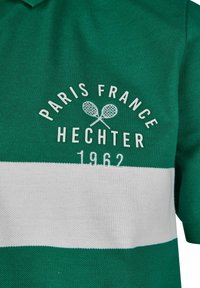 Polo vert avec une rayure horizontale blanche. Présente un texte brodé : "PARIS FRANCE HECHTER" et des raquettes de tennis, année "1962." Le texte est blanc.