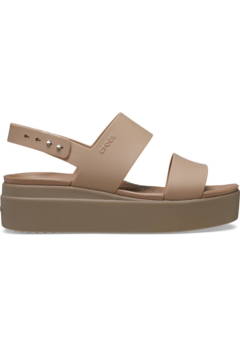 Platform sandalen in zacht beige, gemaakt van gevormd materiaal, met brede banden en een verstelbare enkelriem met zilverkleurige hardware.