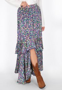 Hosszú, sokszínű, réteges szoknya, amely élénk virágmintával rendelkezik lila, zöld és kék színekben, magas hasító résszel és rugalmas derékpánttal.