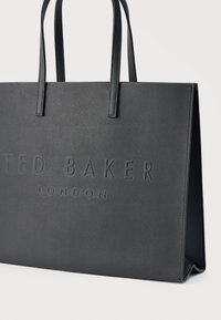 Μαύρη υφασμάτινη τσάντα χειρός με ανάγλυφο λογότυπο «TED BAKER LONDON». Διαθέτει ανθεκτικές λαβές και δομημένο σχήμα, κατάλληλη για καθημερινή χρήση.