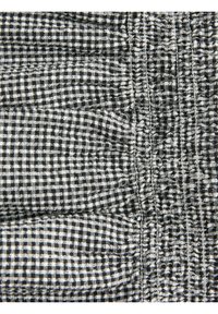 Tissu vichy noir et blanc avec des coutures détaillées et des coutures élastiques froncées créant des sections texturées et plissées.