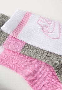 Tri par sock: eni bele z roza detajli, eni svetlo roza in eni sivi. Socke imajo rebraste manšete in mehak tekstur.