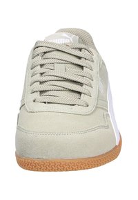 Zapatillas de ante gris claro con cordones planos, acentos laterales blancos y una suela de goma marrón con un patrón texturizado.