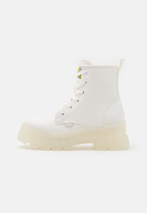 Witte enkellaarzen van textuur materiaal, met een dikke, doorzichtige zool, rechte veters en een aantrek flap aan de achterkant.