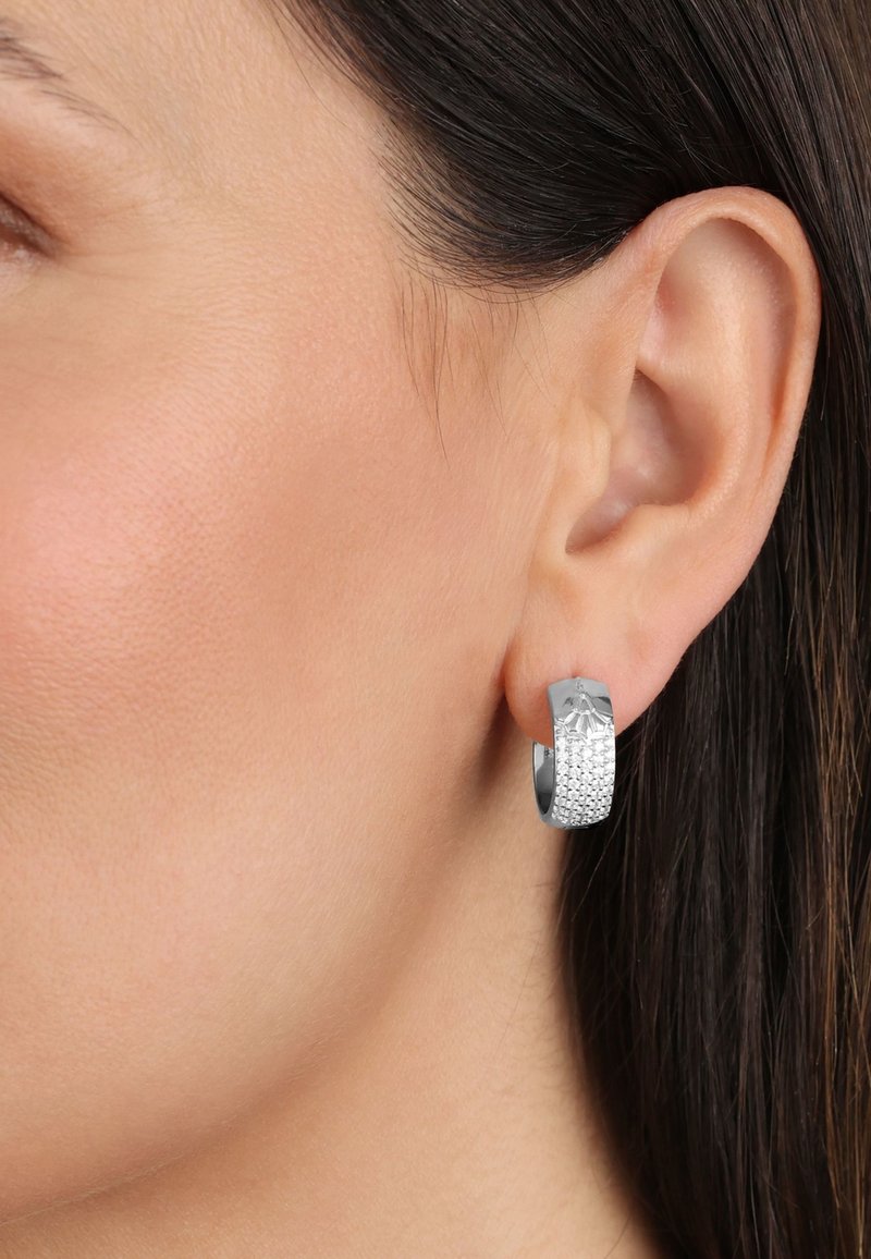 Pendiente de aro de plata texturizada con una sección superior lisa y una sección inferior con un patrón que presenta pequeños detalles en relieve. Apto para orejas perforadas.
