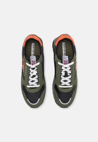 Zapatillas verdes y negras con material de malla y gamuza; cordones blancos; acentos naranjas en el talón; detalle del logo cerca de los cordones.