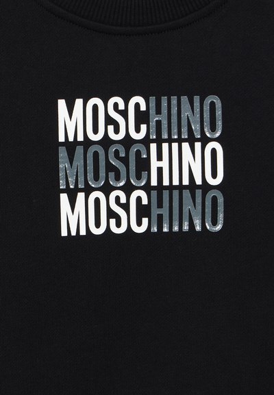 Svart stoff med ordet "MOSCHINO" gjentatt tre ganger i hvite og skinnende grå bokstaver arrangert i et rutenettsmønster.