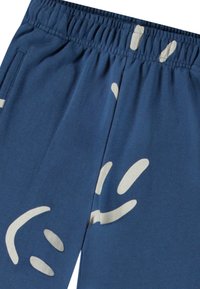 Siniset puuvillajoggerit, joissa on joustava vyötärö, ja ne sisältävät valkoisia abstrakteja muotoja sekä sileän pinnan. Suunnittelussa on sivutaskut.