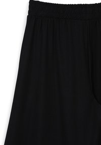 Pantaloni neri con vita elastica e tessuto liscio. Presentano una cintura arricciata e una vestibilità morbida, pensati per il comfort e la libertà di movimento.