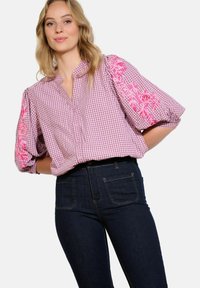 Blusa a quadri rosa e bianca con maniche a sbuffo, caratterizzata da ricami floreali rosa sulle maniche, pattina con bottoni e vestibilità rilassata.