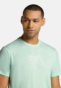 Licht mintgroen T-shirt met korte mouwen, gemaakt van zachte stof, met een witte fietsafbeelding en een ronde halslijn. Subtiele textuur zichtbaar.