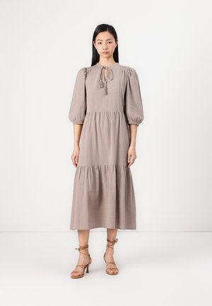 Mauve midi dress with puff sleeves, tie detail at the neck, and tiered skirt. Paired with strappy beige heels. Smooth, lightweight fabric.