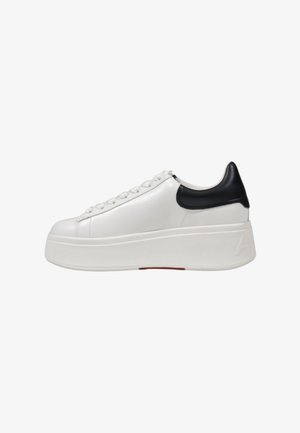 Zapatilla de cuero blanca con suela blanca gruesa y acento negro en el talón. Presenta cordones planos y un acabado suave, destacando un diseño minimalista.
